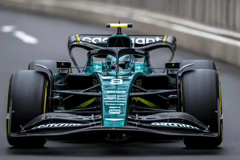 Max Verstappen driving an Aston Martin Formula 1 car at high speed on a racetrack. He’s wearing a green Aston Martin race suit and custom helmet, tightly seated in the cockpit as he takes a sharp corner. The car features the iconic metallic British racing green livery, gleaming under track lighting. The scene is dramatic and unexpected, suggesting a bold shift in F1 dynamics