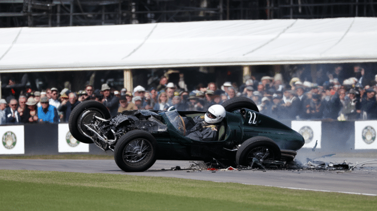 A dramatic moment from the Goodwood Festival of Speed, capturing a shocking crash involving a vintage Formula 1 car. The green single-seater is mid-air, its front-end shattered, with debris scattered across the track. The driver, wearing a white helmet, appears alert inside the cockpit. Spectators in the background watch in disbelief. The image highlights the chaos of the crash and the miraculous survival of the driver.
