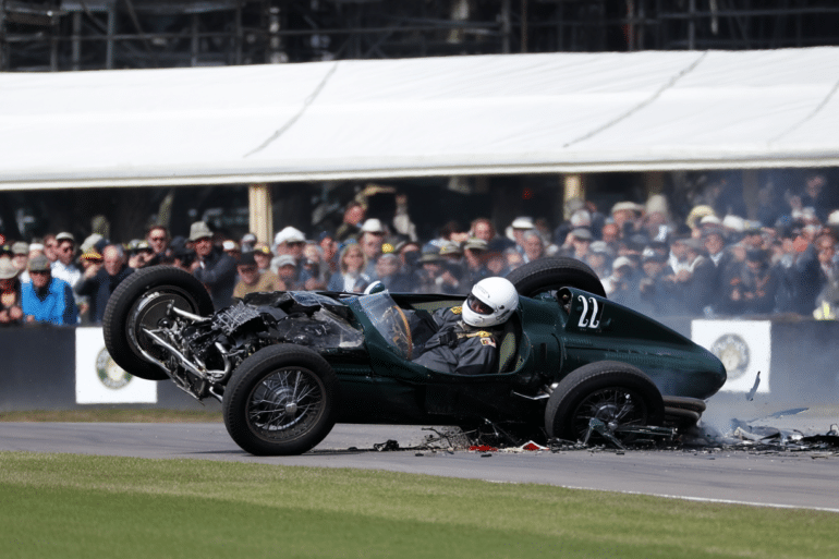 A dramatic moment from the Goodwood Festival of Speed, capturing a shocking crash involving a vintage Formula 1 car. The green single-seater is mid-air, its front-end shattered, with debris scattered across the track. The driver, wearing a white helmet, appears alert inside the cockpit. Spectators in the background watch in disbelief. The image highlights the chaos of the crash and the miraculous survival of the driver.