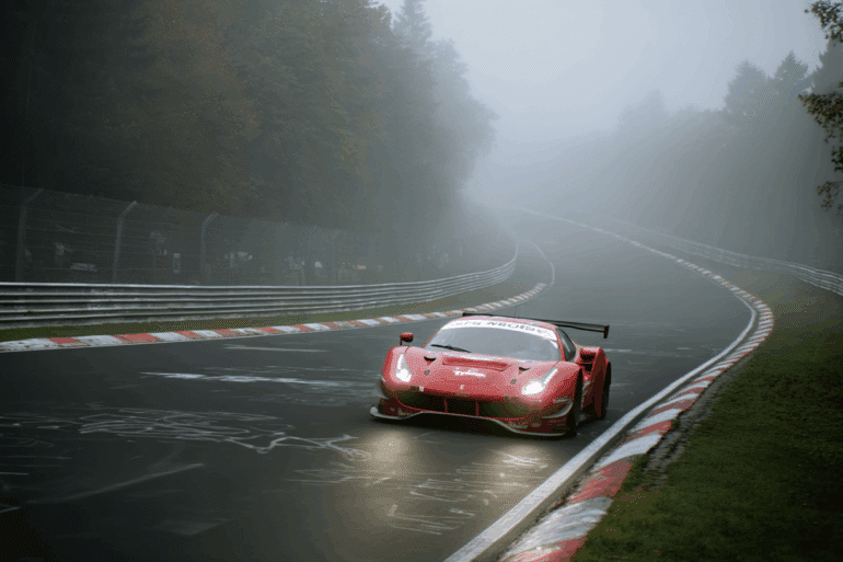 A Ferrari GT3 race car powers through a tight corner on a foggy, damp Nürburgring Nordschleife during a secret test session. The red car’s headlights pierce the mist, with no crowd present — only wet track, graffiti-covered tarmac, and quiet forest surroundings creating a focused and stealthy testing atmosphere.